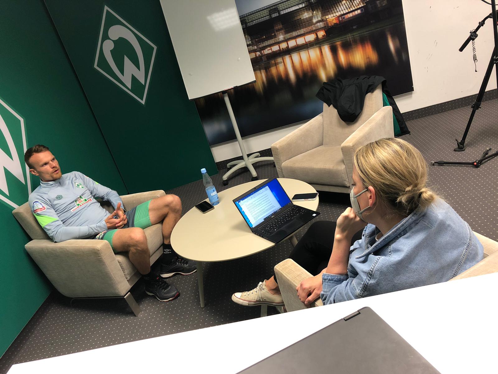 Eine blonde Frau interviewt einen Fußballspieler